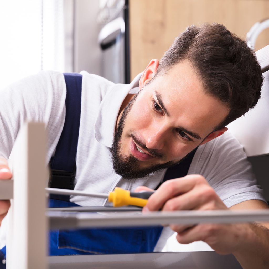Person installing drawer with a screwdriver