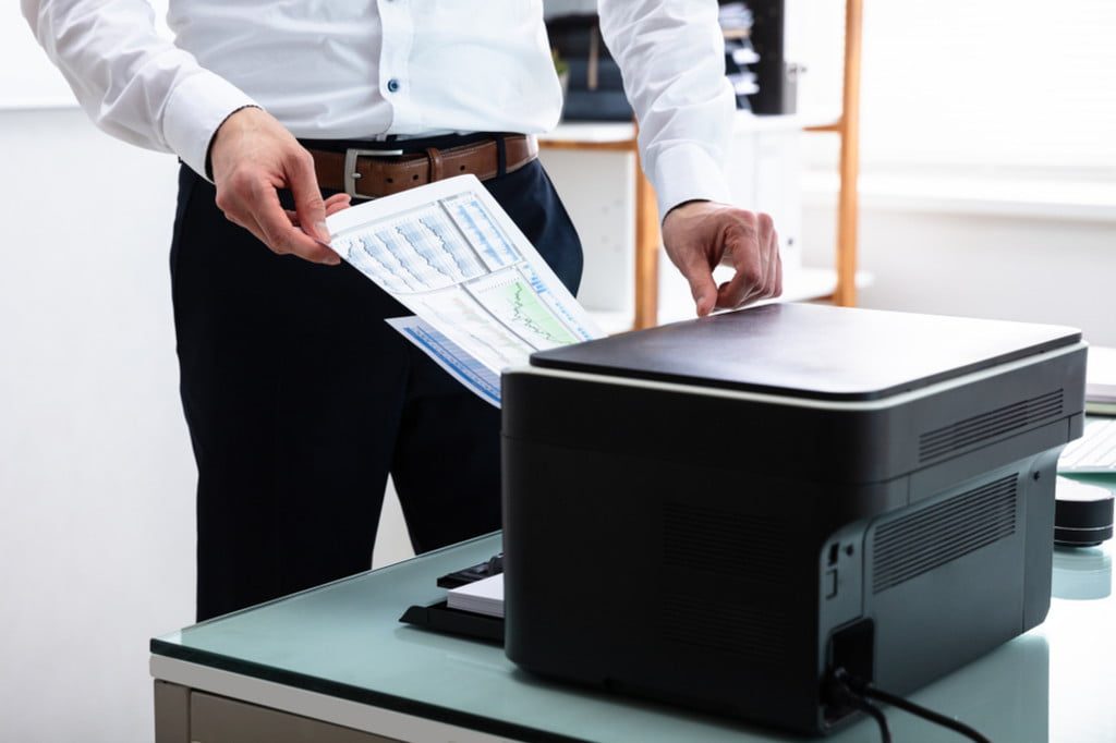 Person loading paper into office printer/copy machine
