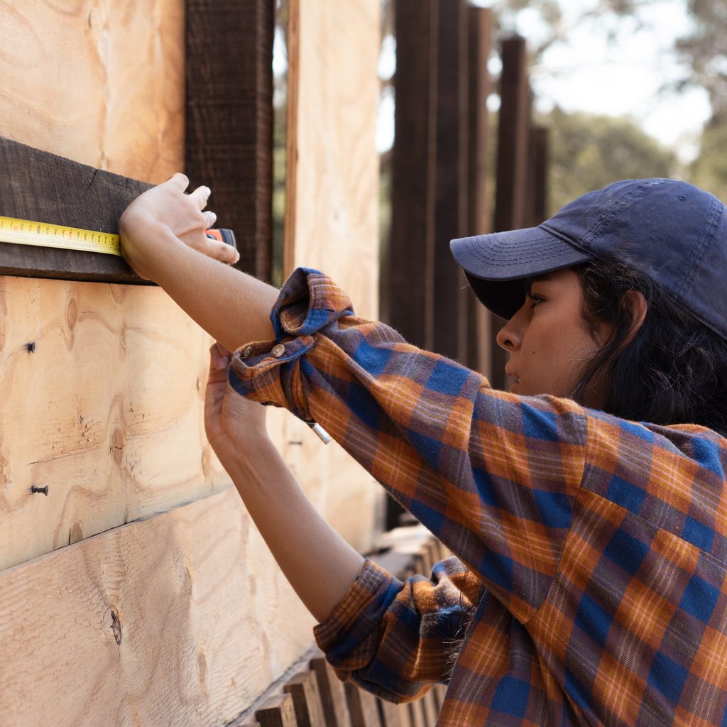 Female carpenter using measuring tape