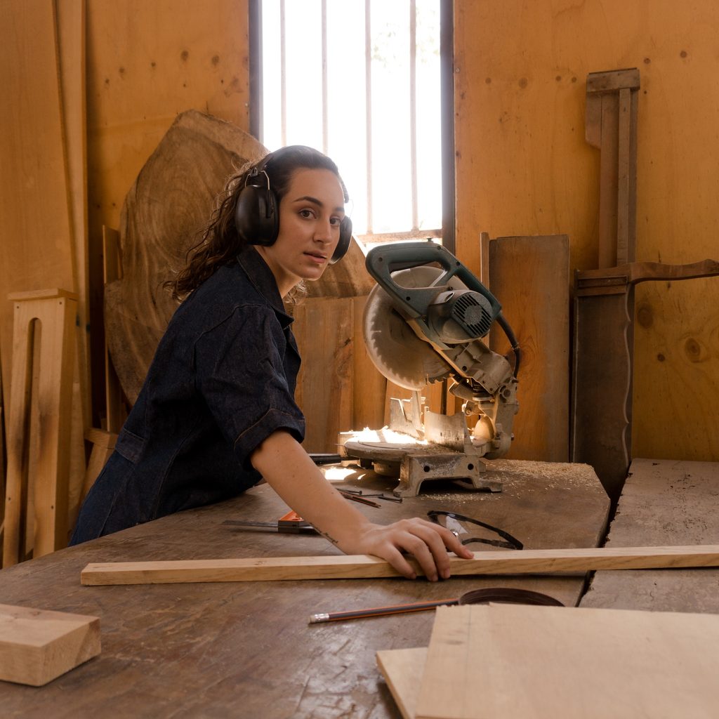 Female carpenter sawing a board