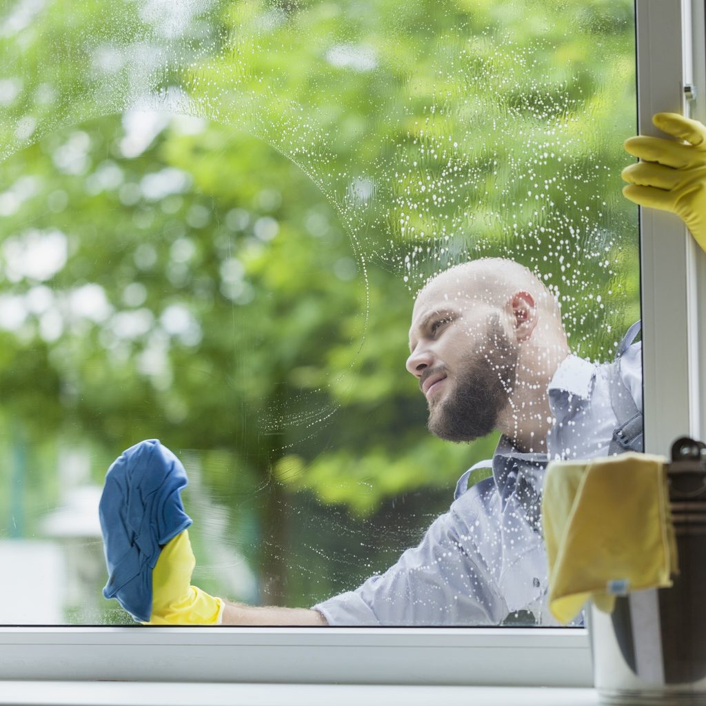 Man with beard washing a window