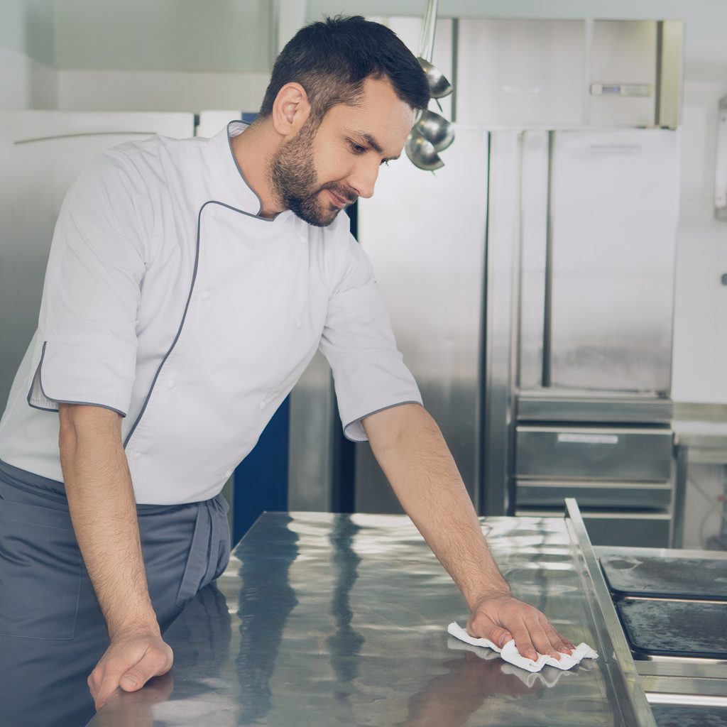 man wiping down kitchen counter