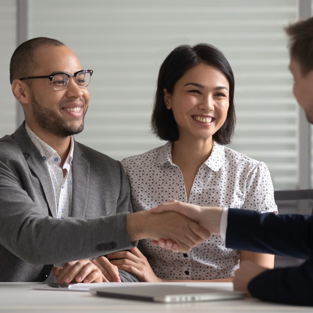 Interracial couple shaking hands with banker