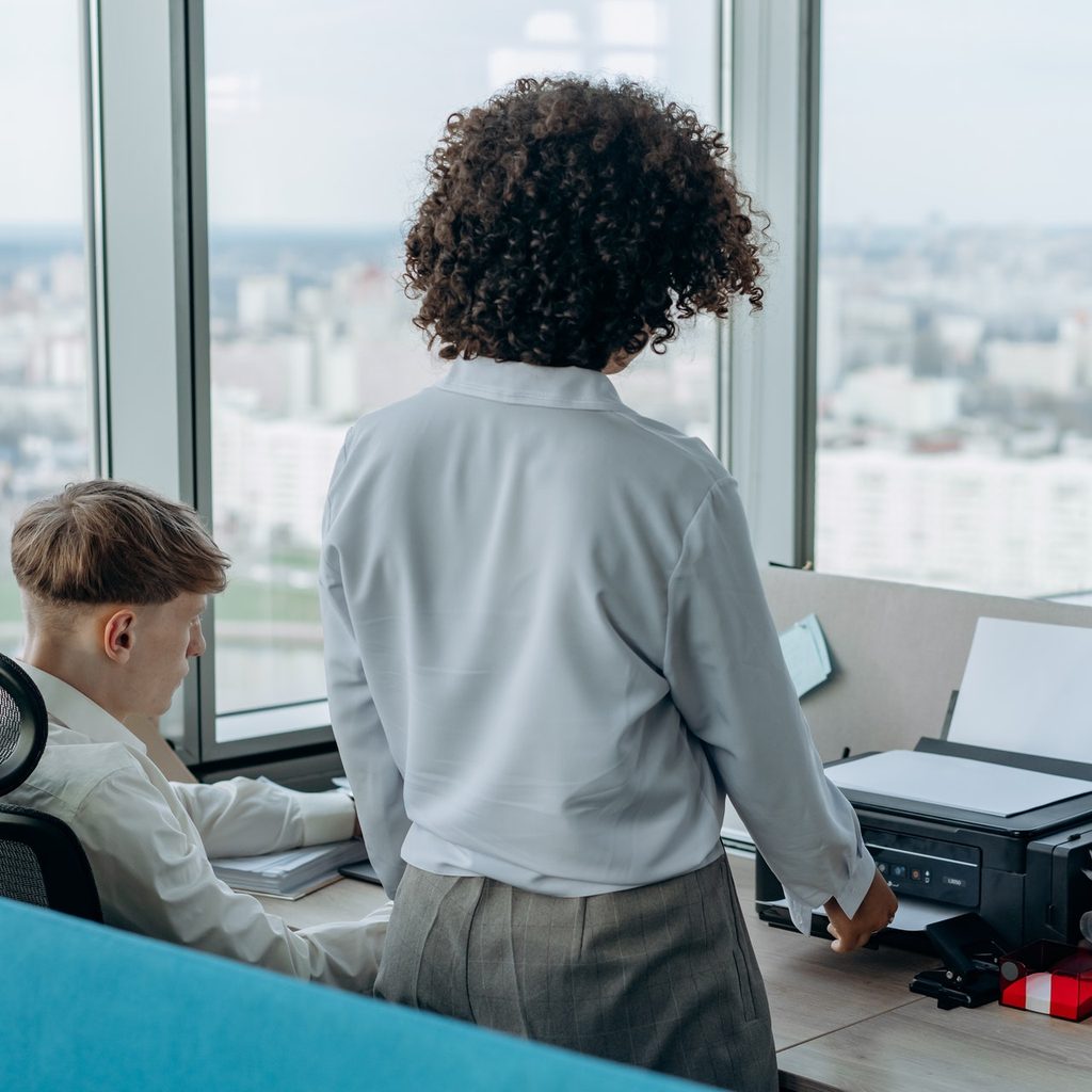 Two people at a desk with a copy machine/printer