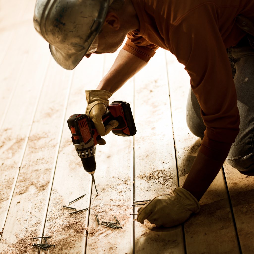 Contractor using a cordless drill on a wood floor