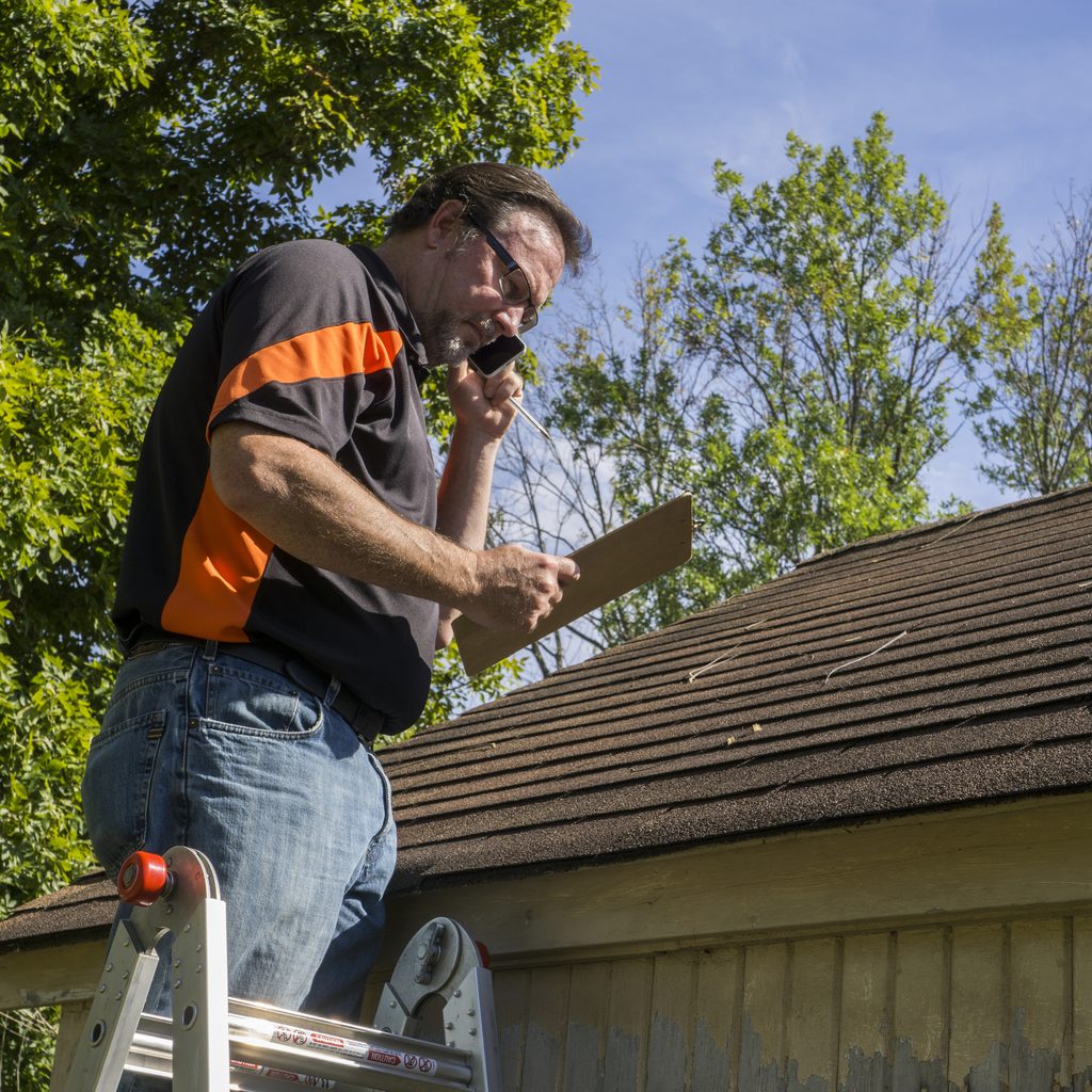 Roofer on a ladder working on a roof estimate
