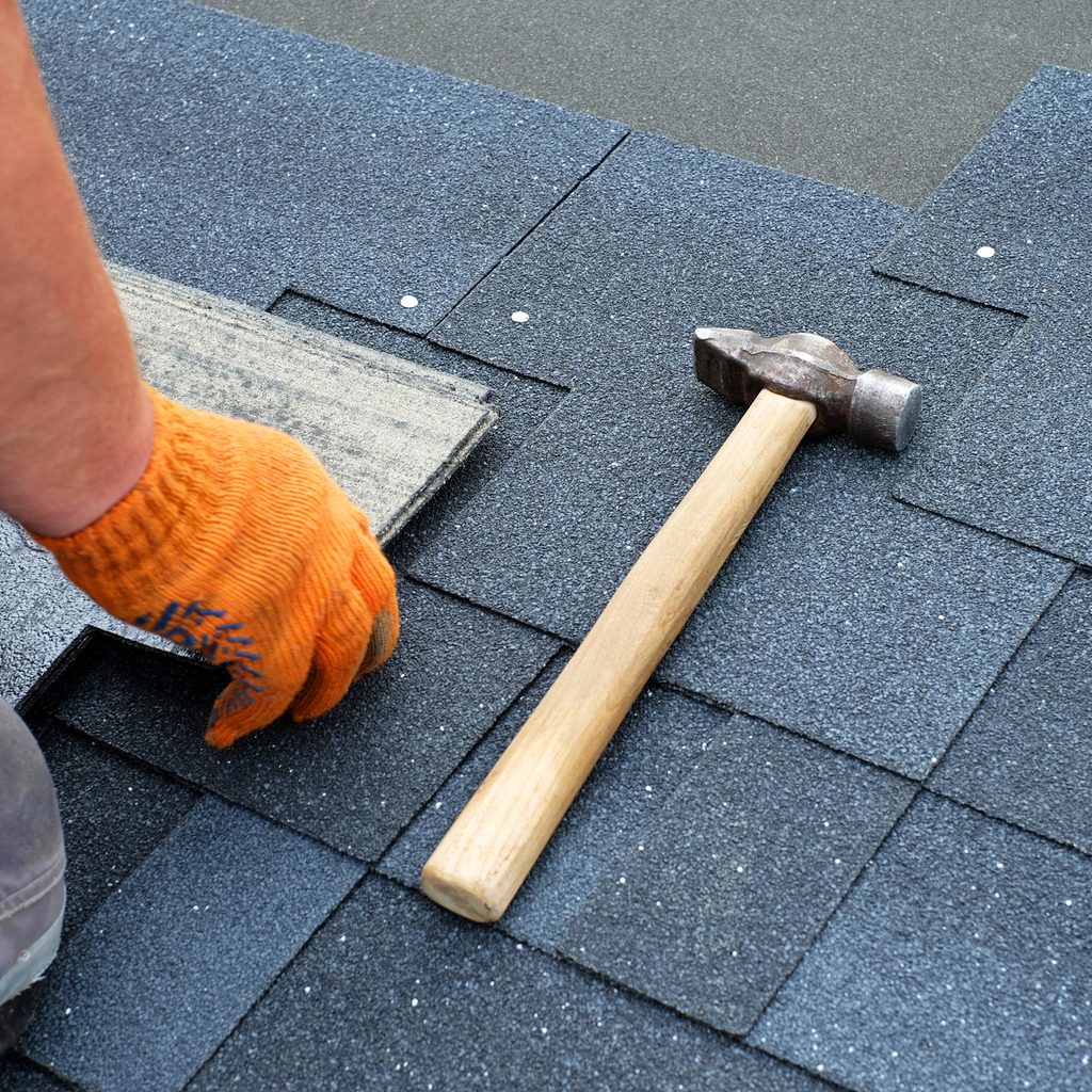 Hammer and nails installing shingles on a roof