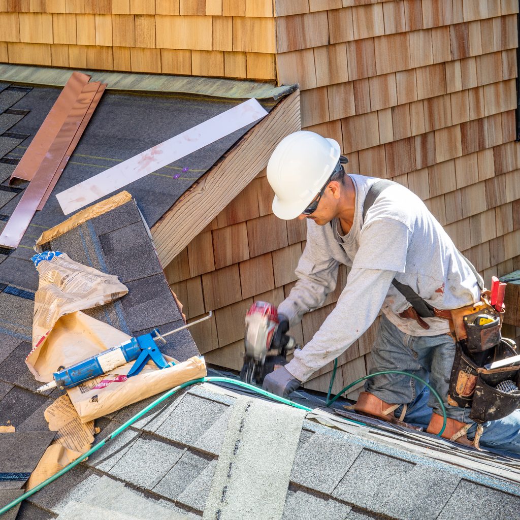 Roofer building roof with shingles