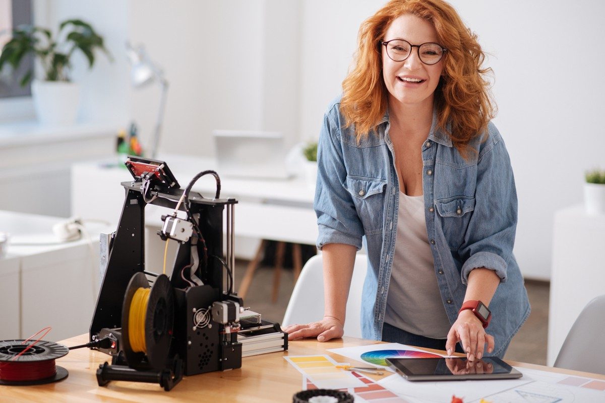 Happy cheerful nice woman standing at the table and smiling while being in a great mood