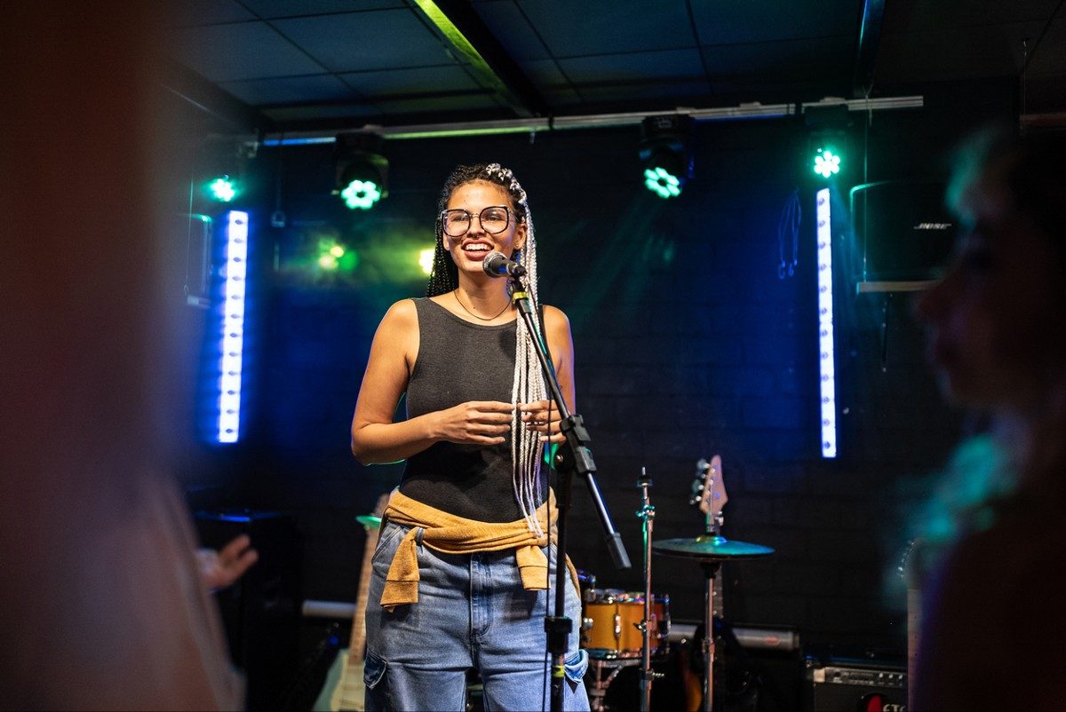 Young woman talking during stand-up comedy show with with stage lights