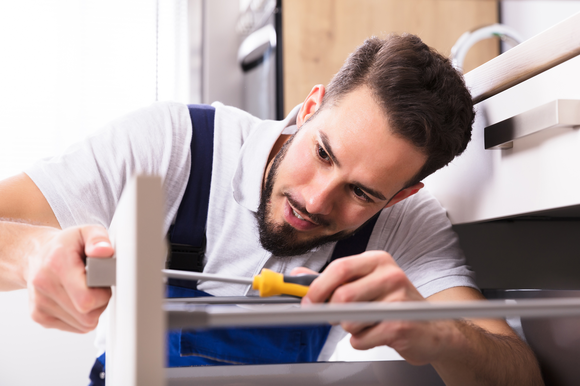Person installing drawer with a screwdriver