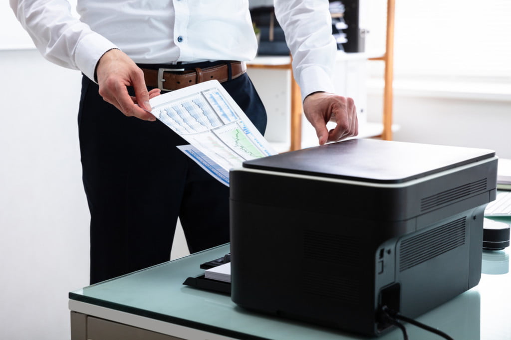 Person loading paper into office printer/copy machine