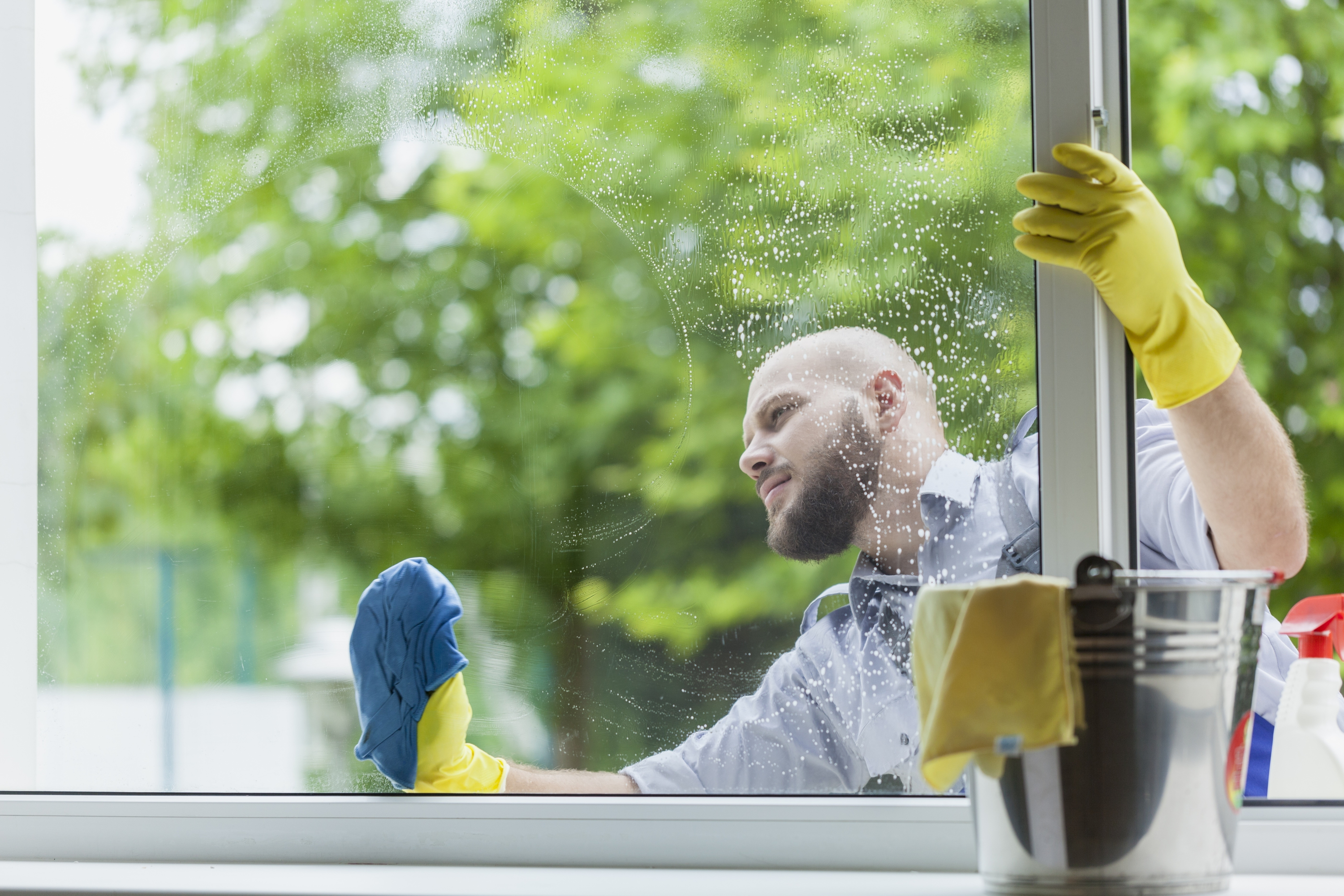 Man with beard washing a window