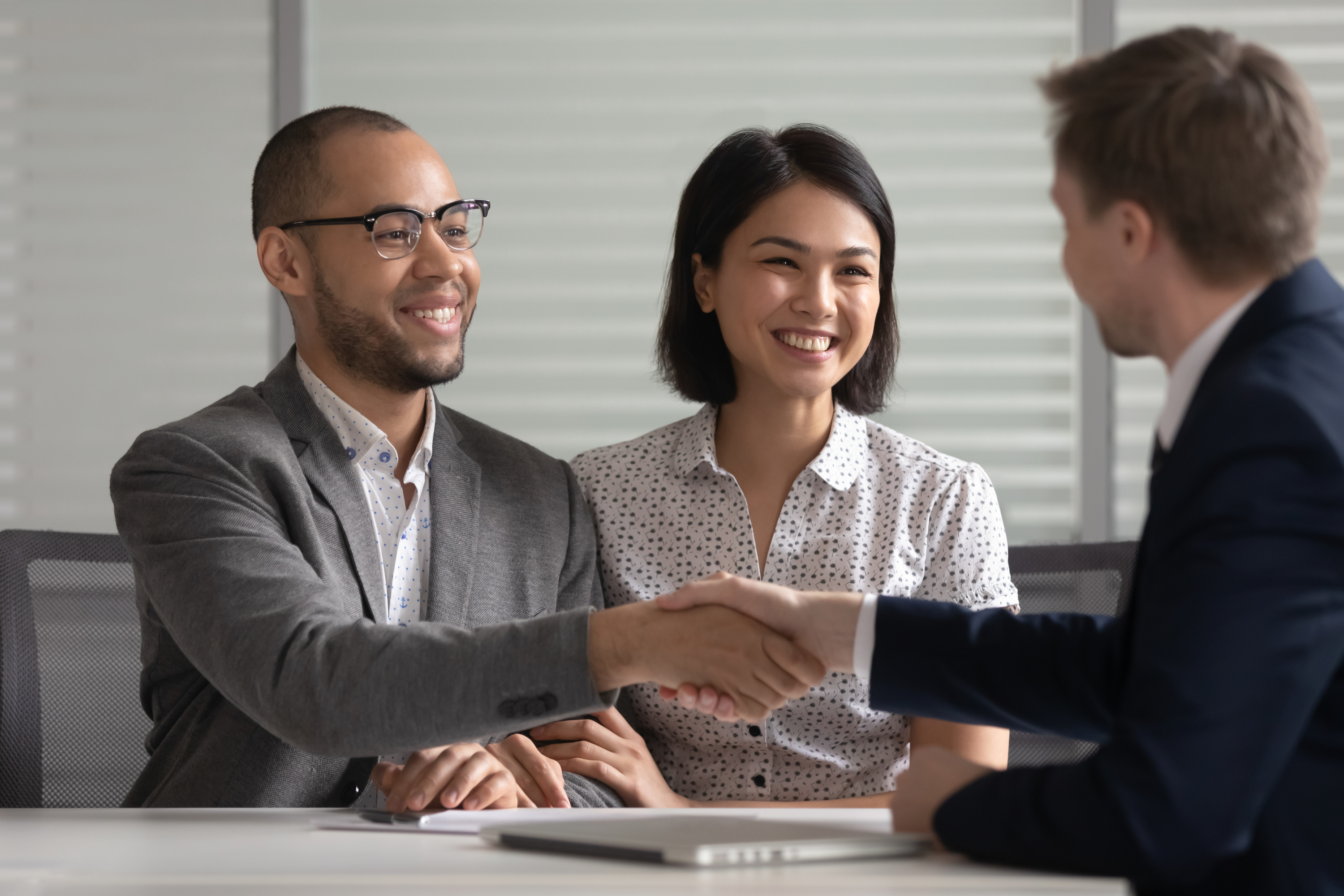 Interracial couple shaking hands with banker