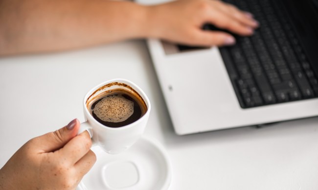 morning habits leaders coffee break at workplace  woman typing on laptop and holding