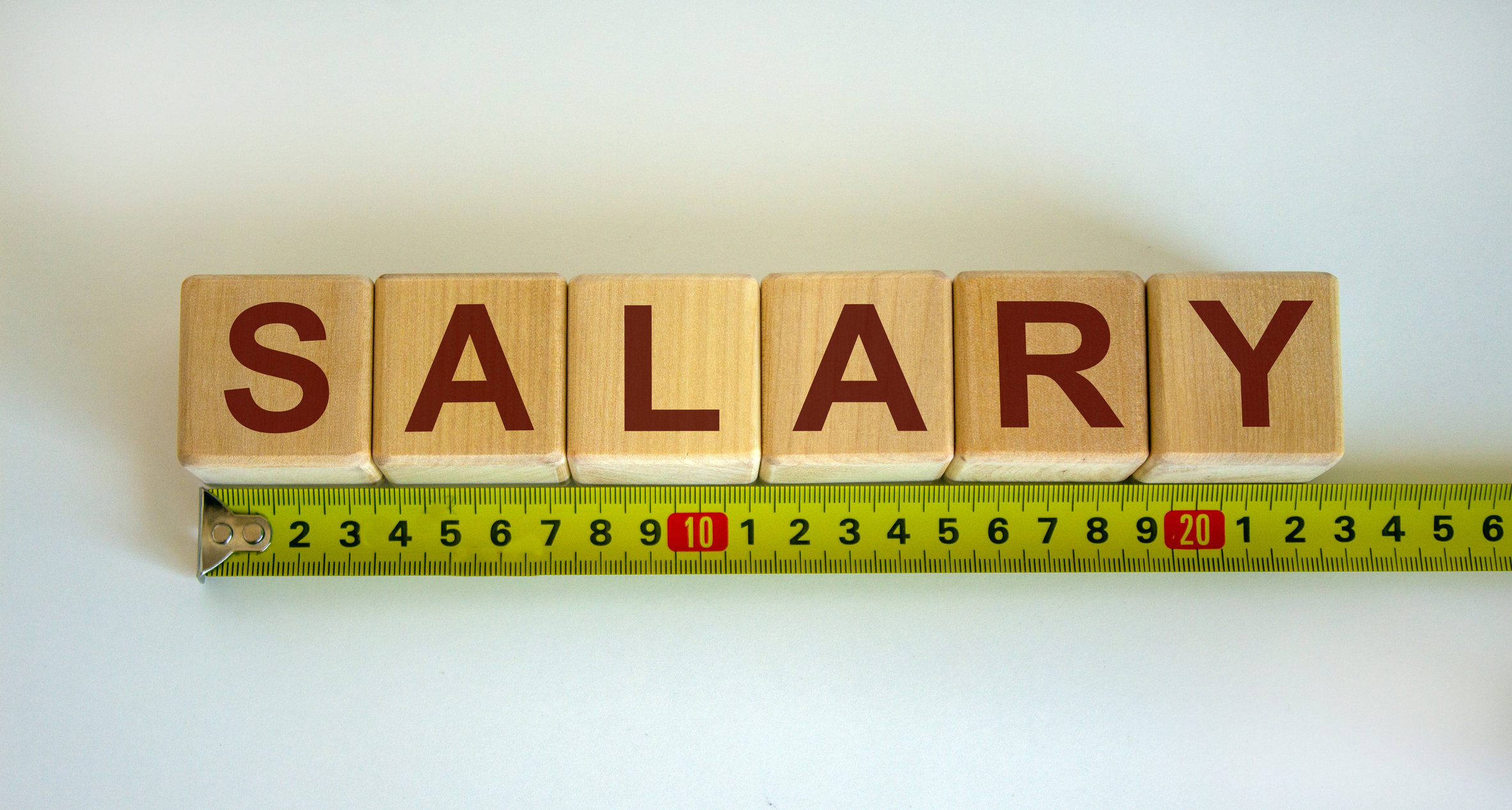 "Salary" word on cubes arranged behind a ruler