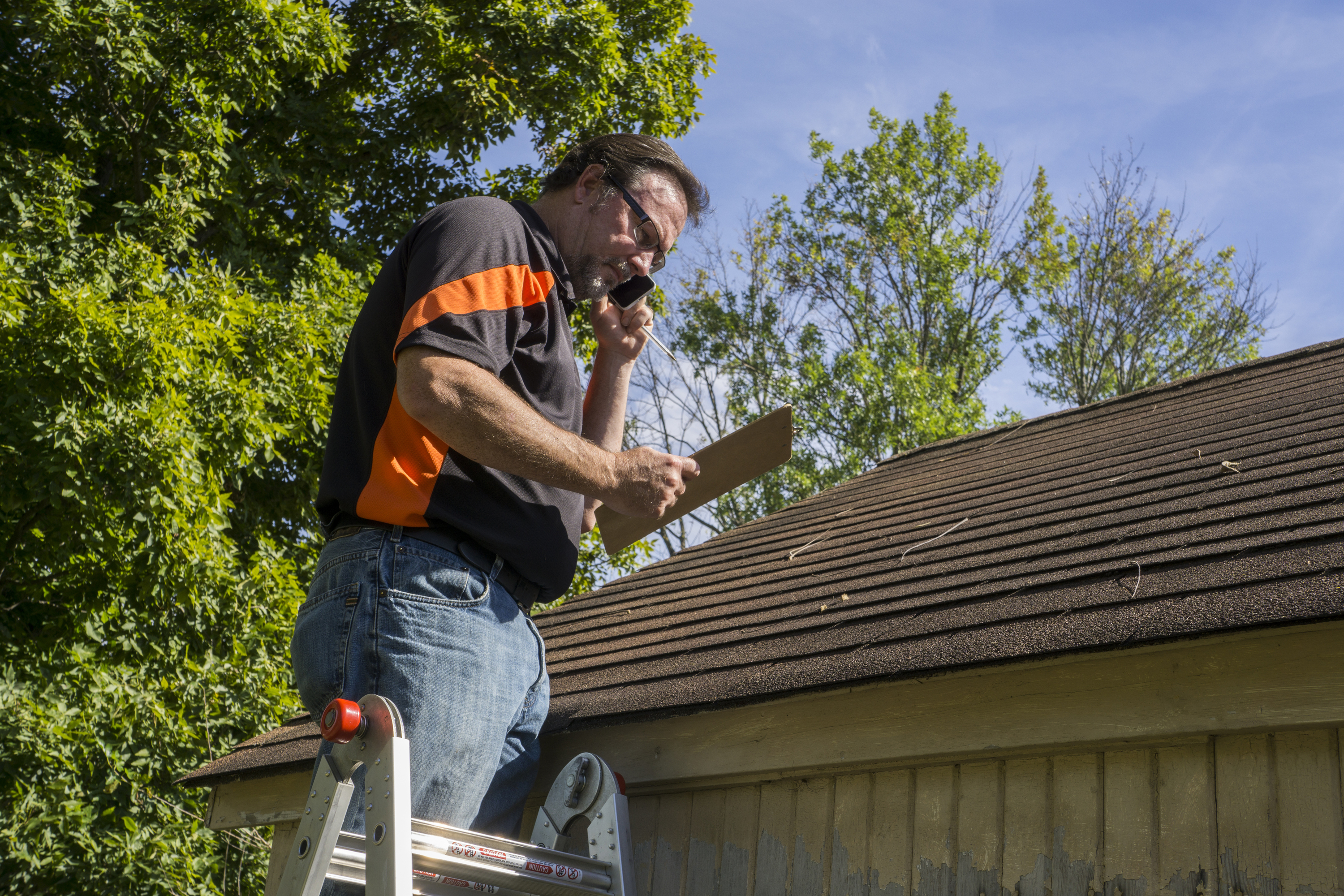 Roofer on a ladder working on a roof estimate