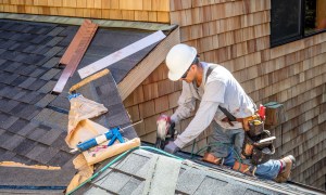 Roofer building roof with shingles