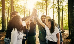 Coworkers high five outdoors on a teambuilding retreat