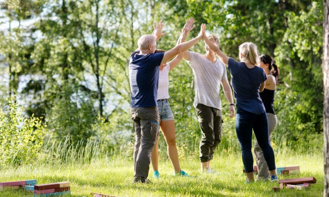 Coworkers high five outdoors after doing a team building exercise