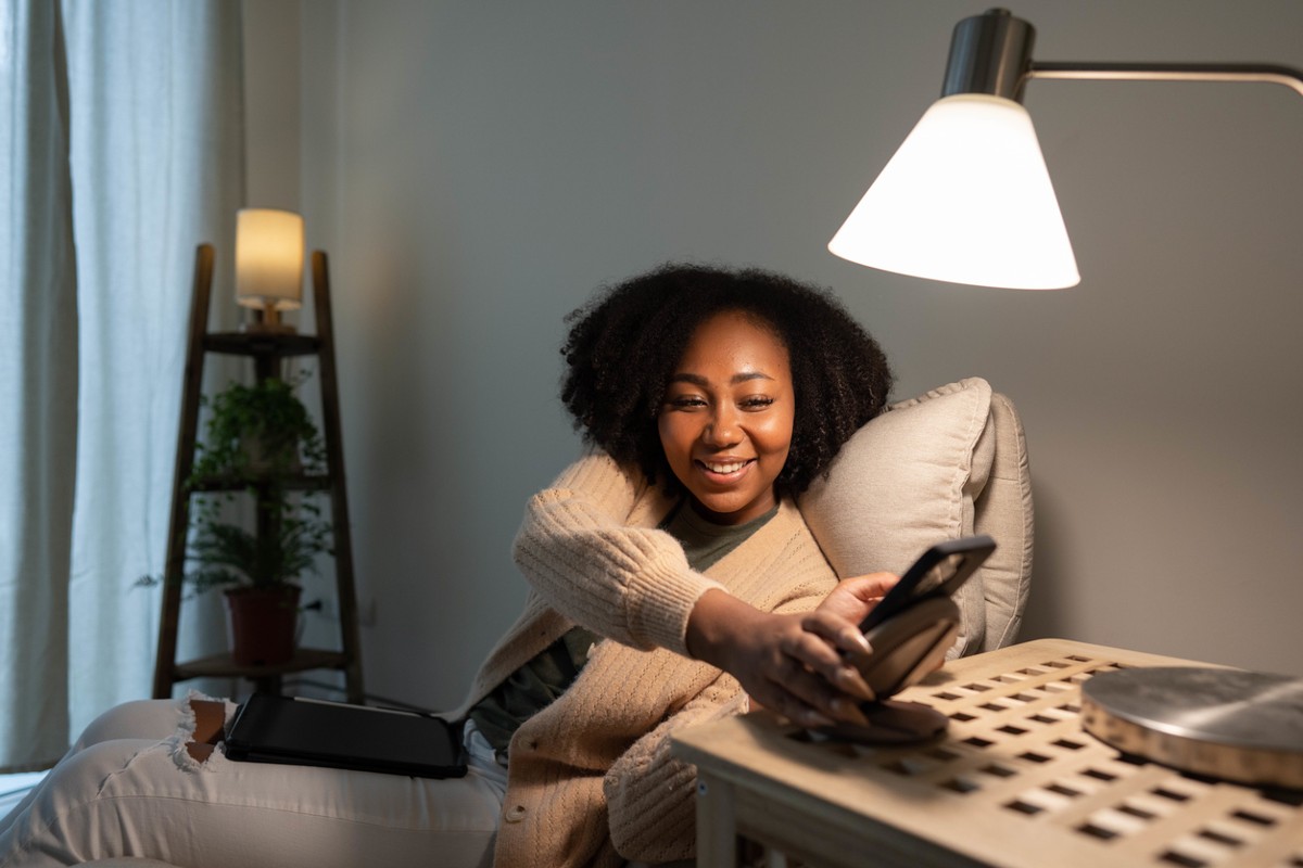 Young woman using mobile phone being placed on a modern wireless power bank.