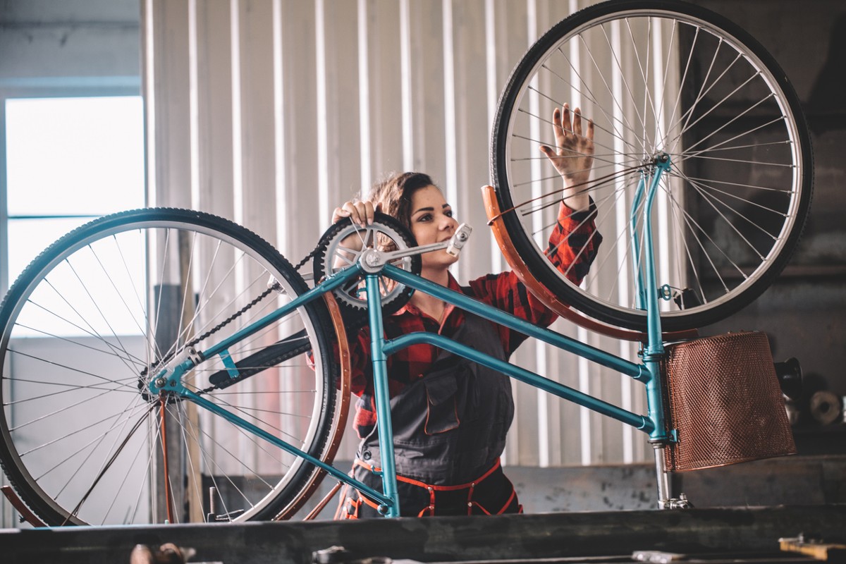Woman repairing bicycle in workshop