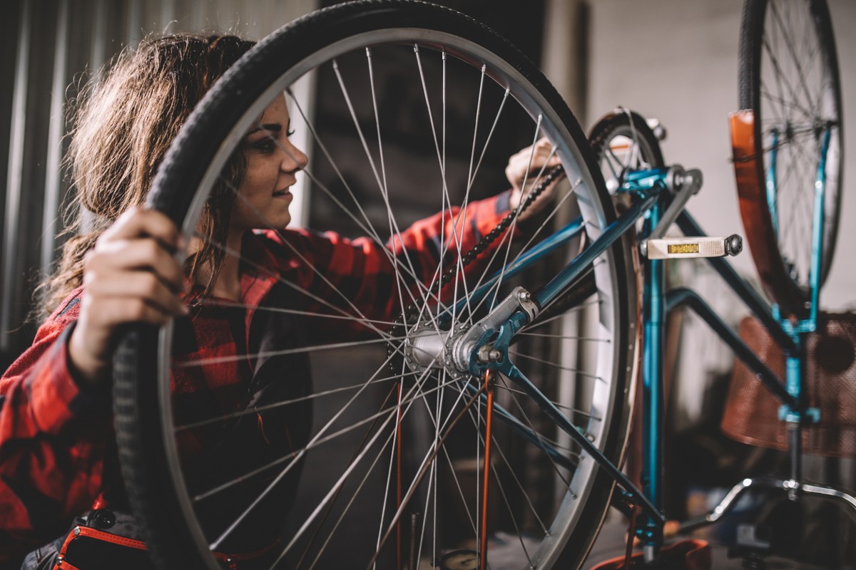 Beautiful woman repairing bicycle in garage